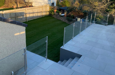 Modern patio and outdoor living space completed in Bristol with porcelain paving and glass balustrades.