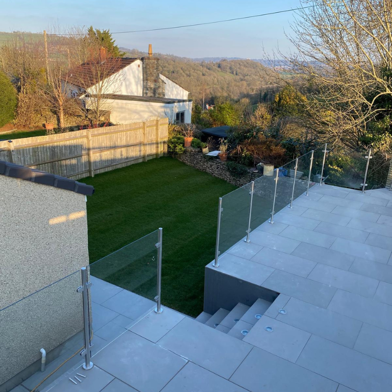 Raised patio area with glass balustrade overlooking landscaped garden.